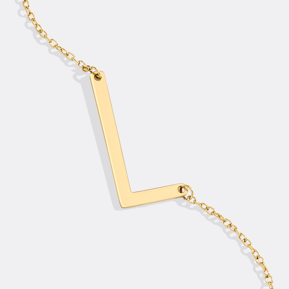 Gold V-shaped necklace on a light gray background