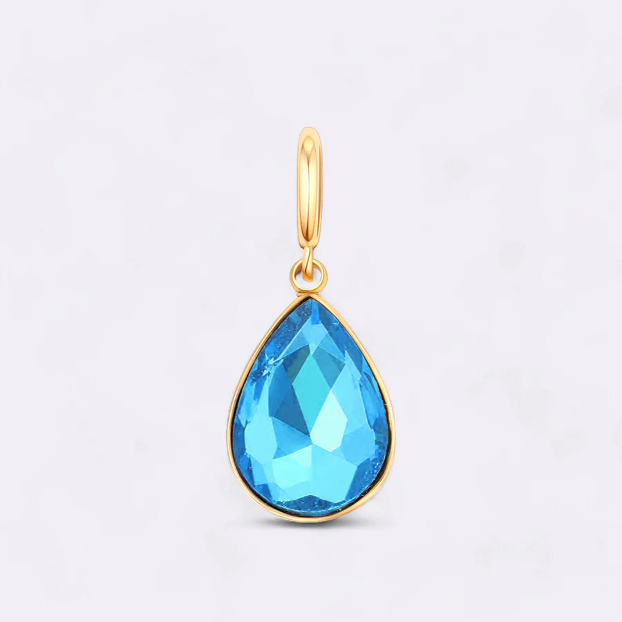 Gold pendant with a blue teardrop-shaped gemstone on a light gray background
