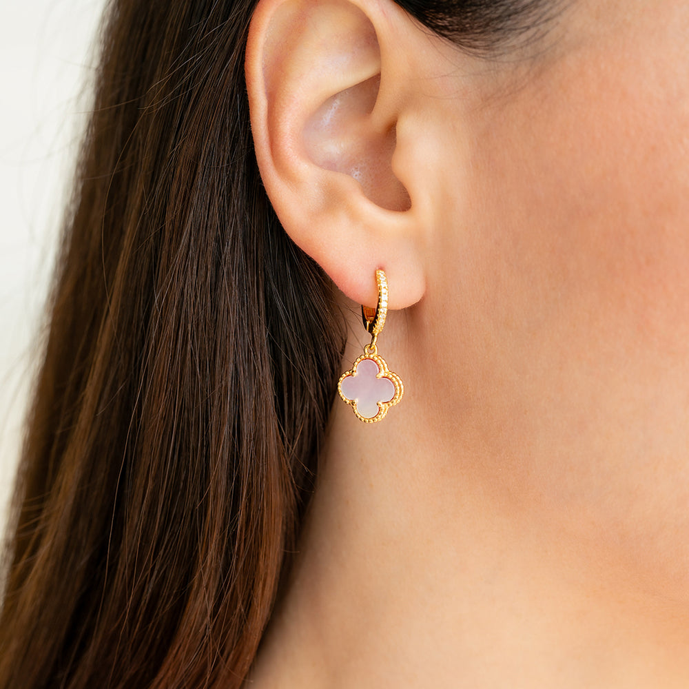 Gold earring with a pink stone worn by a person