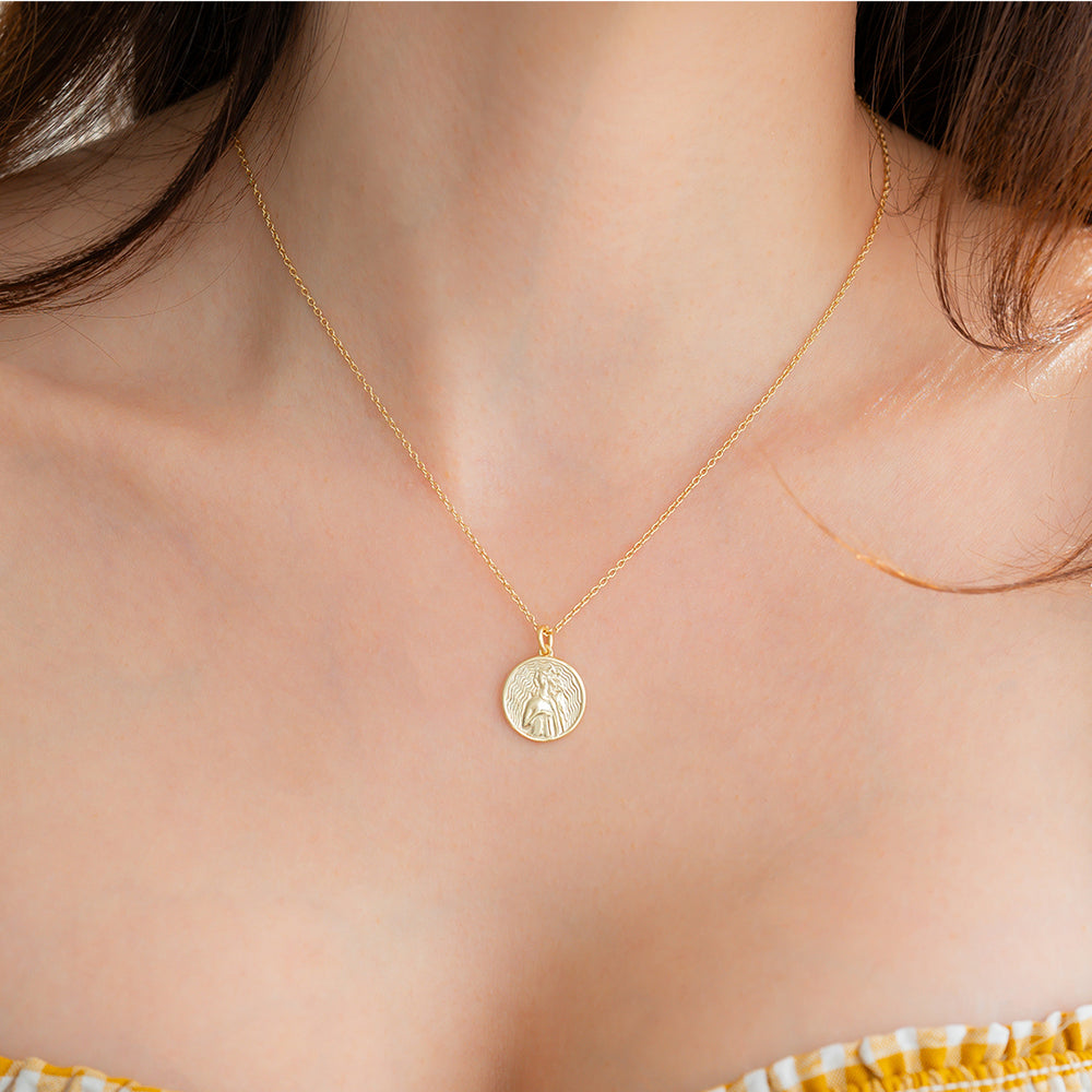 Gold necklace with a pendant on a person's neck