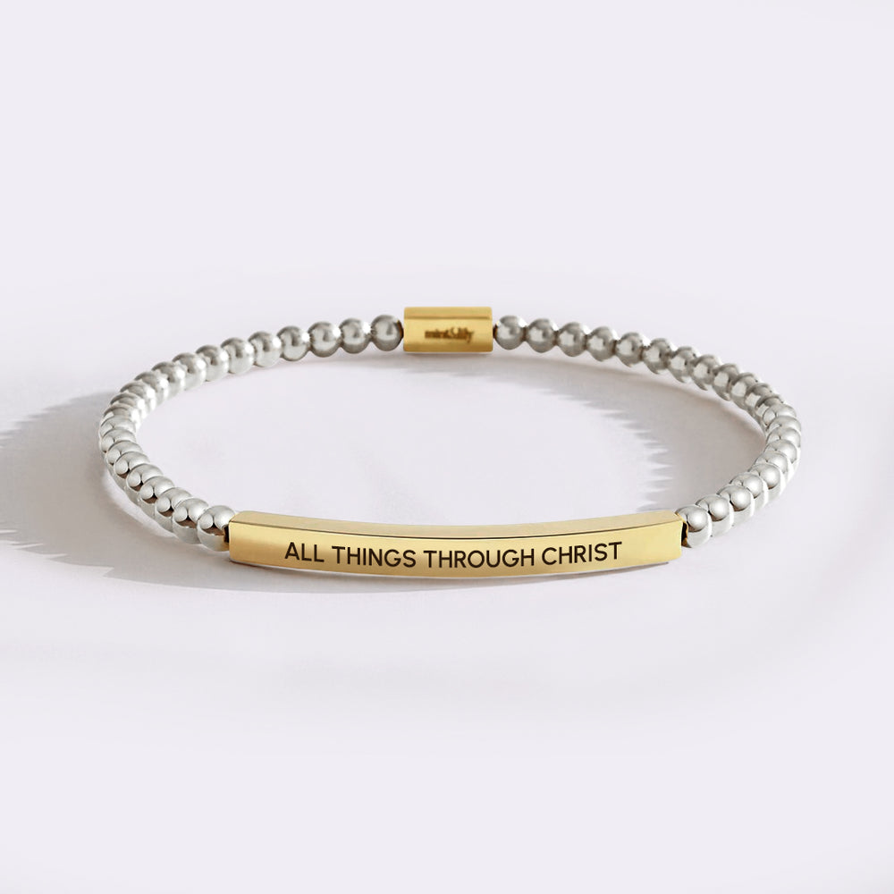 Bracelet with gold tag reading 'All Things Through Christ' on a white background