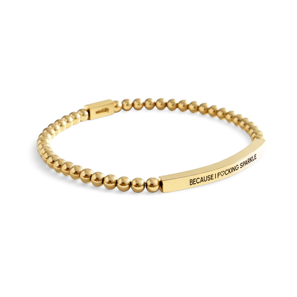 Gold beaded bracelet with a engraved message on a light background