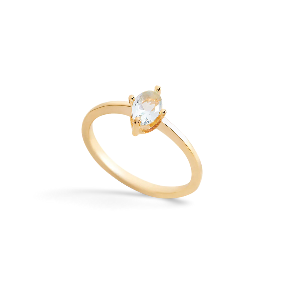 Gold ring with a clear gemstone on a light gray background