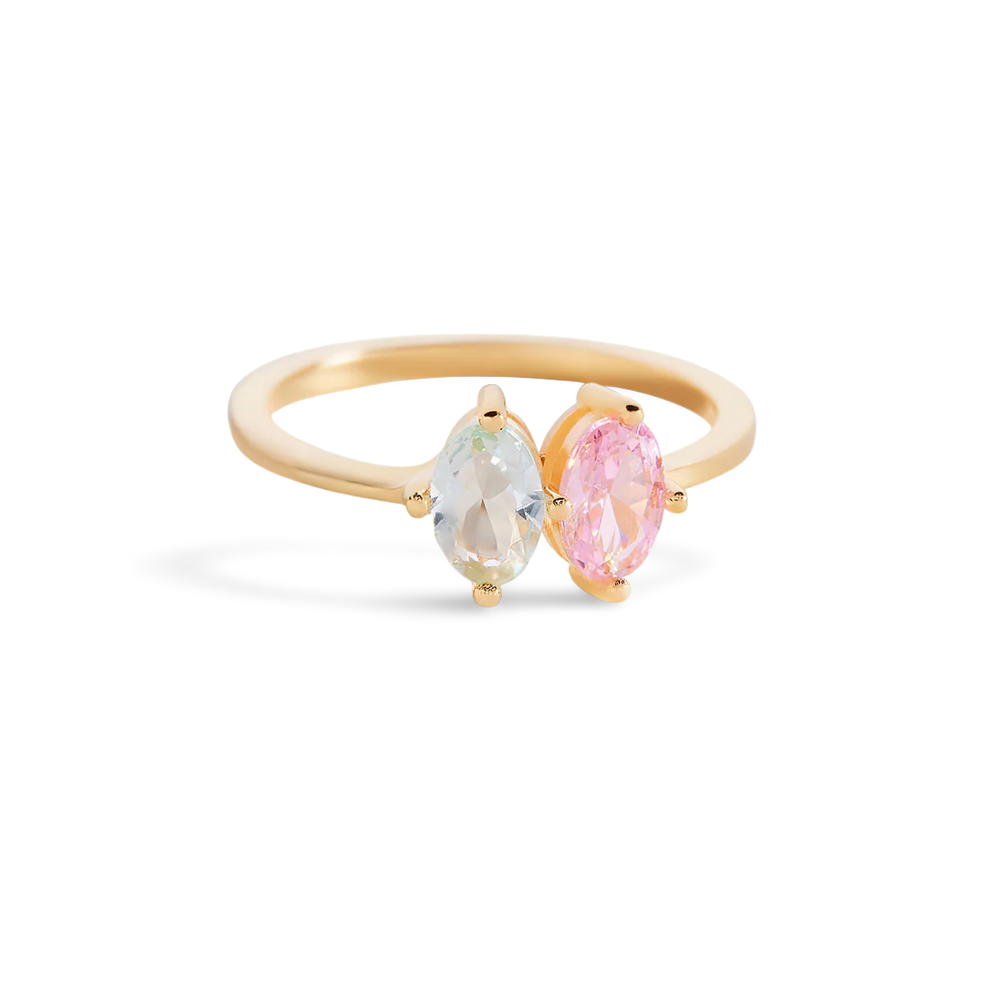 Gold ring with two pear-shaped gemstones on a light background