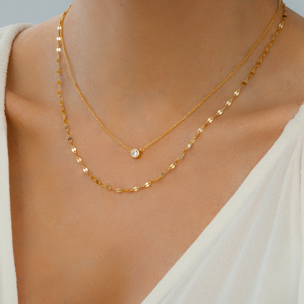 Gold chain necklace on a person wearing a white top