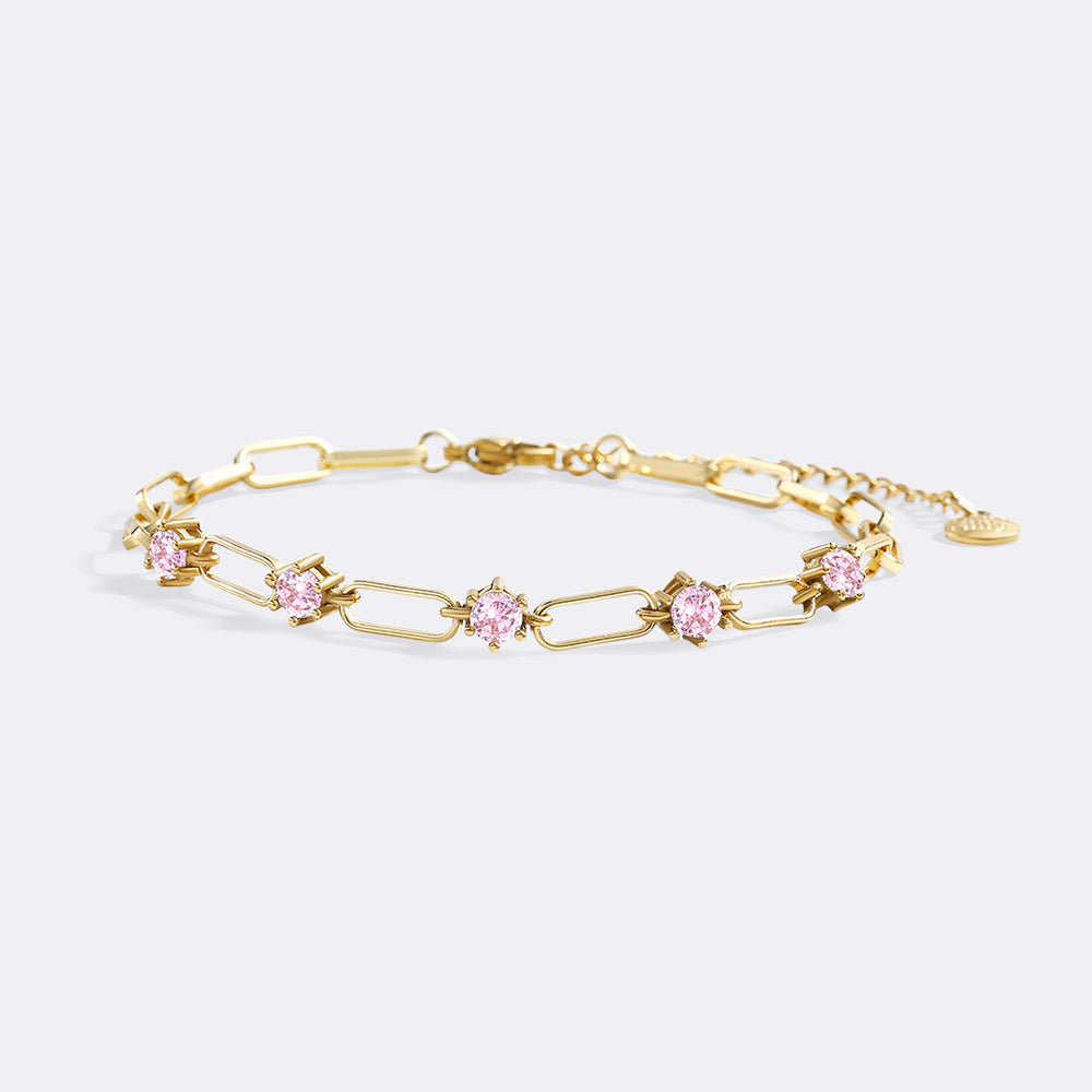 Gold bracelet with pink gemstones on a light gray background