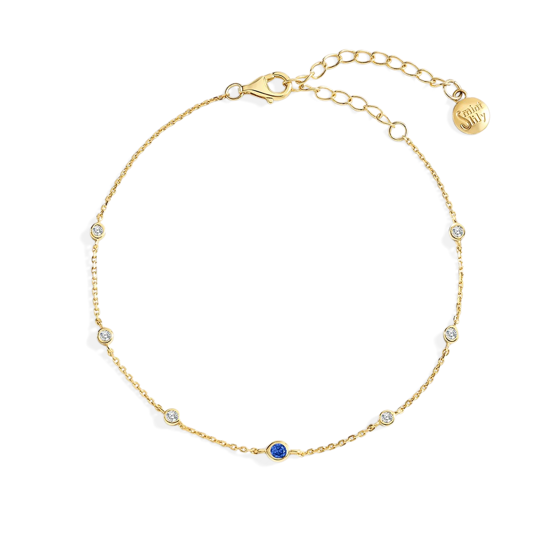 Gold bracelet with small gemstones on a light gray background