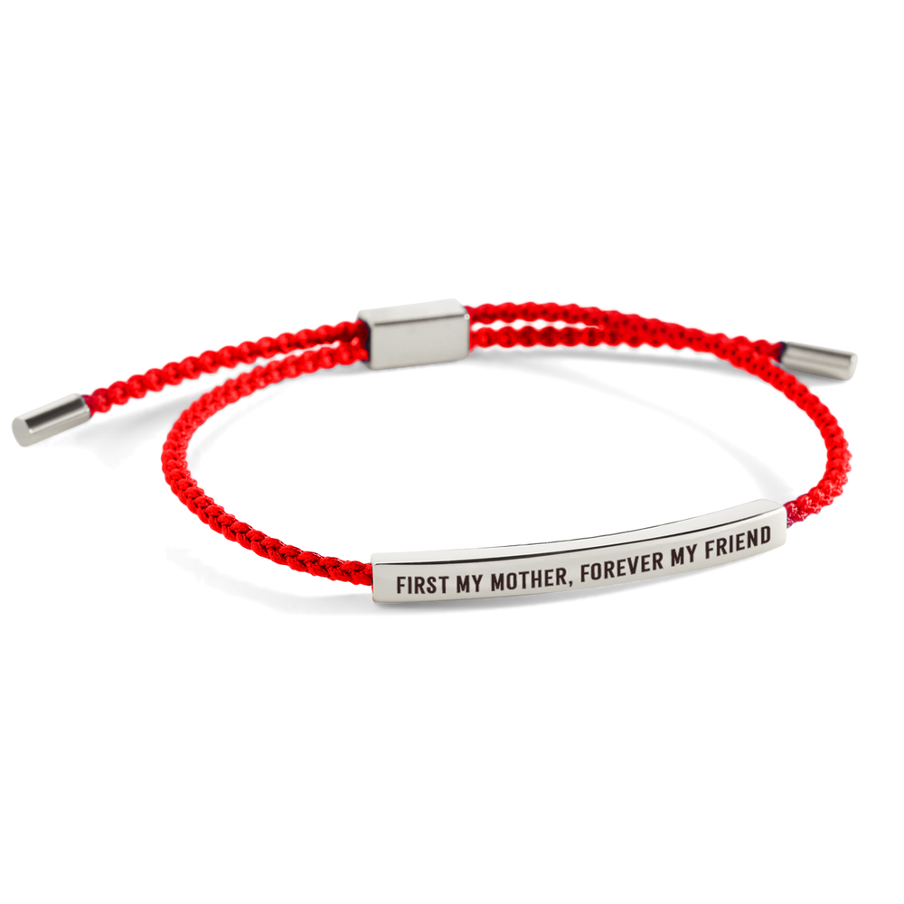 A dark-colored bracelet with metal accents and an inscription that reads 'first my mother, forever my friend'.