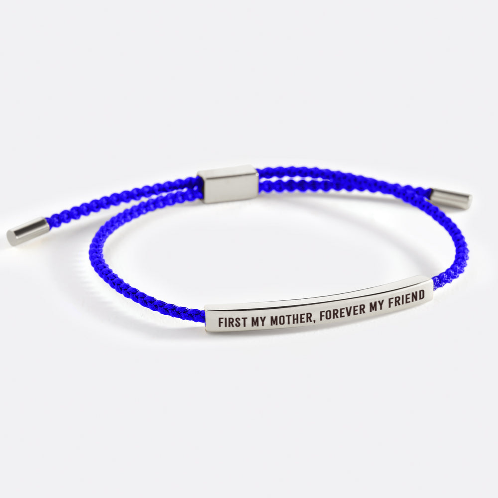A dark-colored bracelet with metal accents and an inscription that reads 'first my mother, forever my friend'.