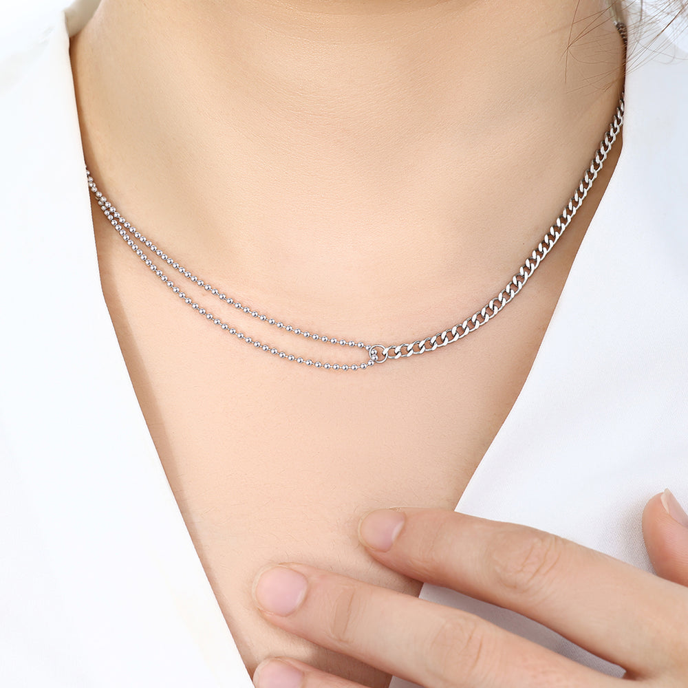 Silver chain bracelet on a person's wrist with a plain background