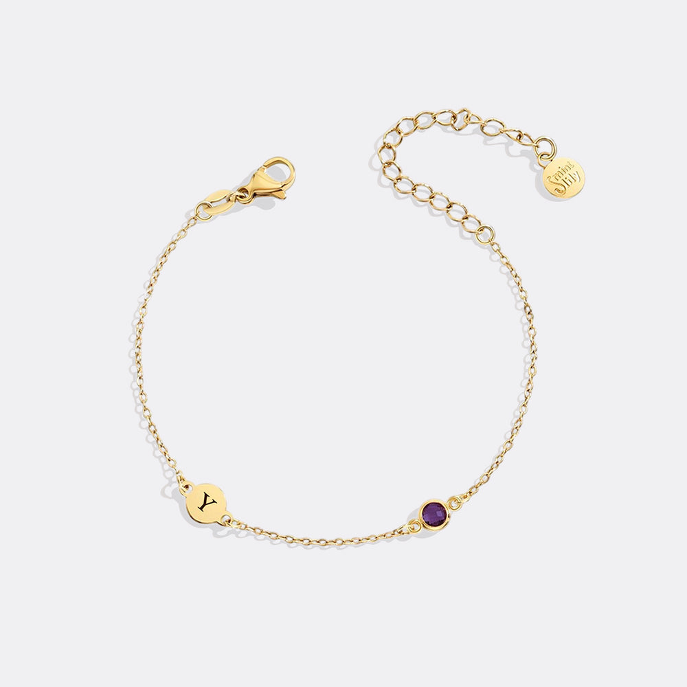 Gold bracelet with a purple gemstone on a white background