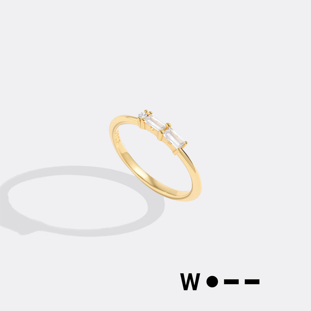 Gold ring with a clear gemstone on a light gray background