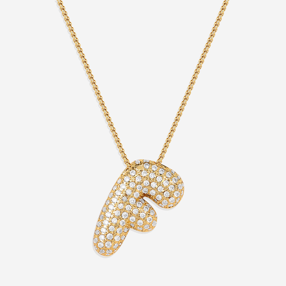 A gold initial necklace with a bubble-shaped pendant covered in zircon stones, displayed against a black background.
