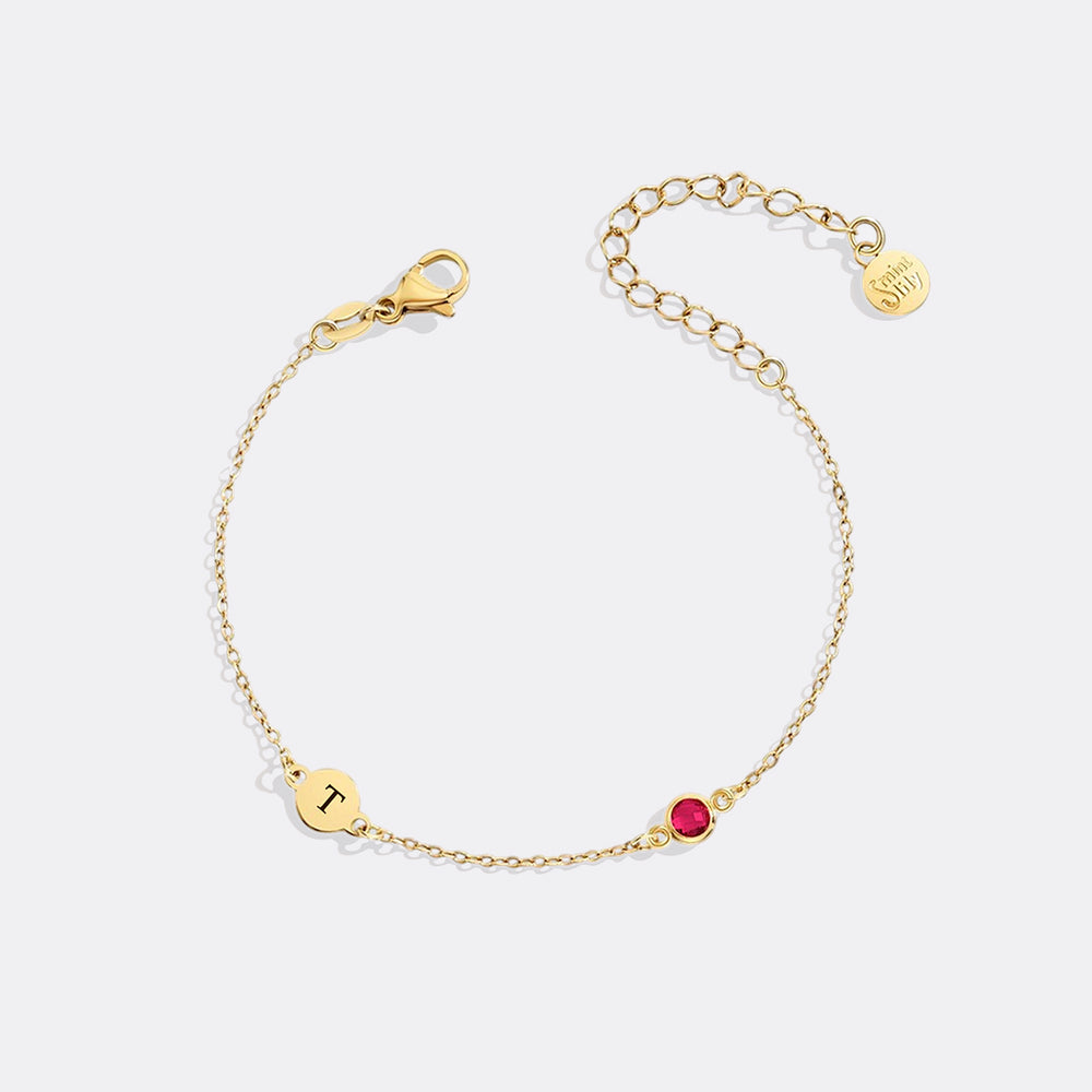 Gold bracelet with a red gemstone on a white background