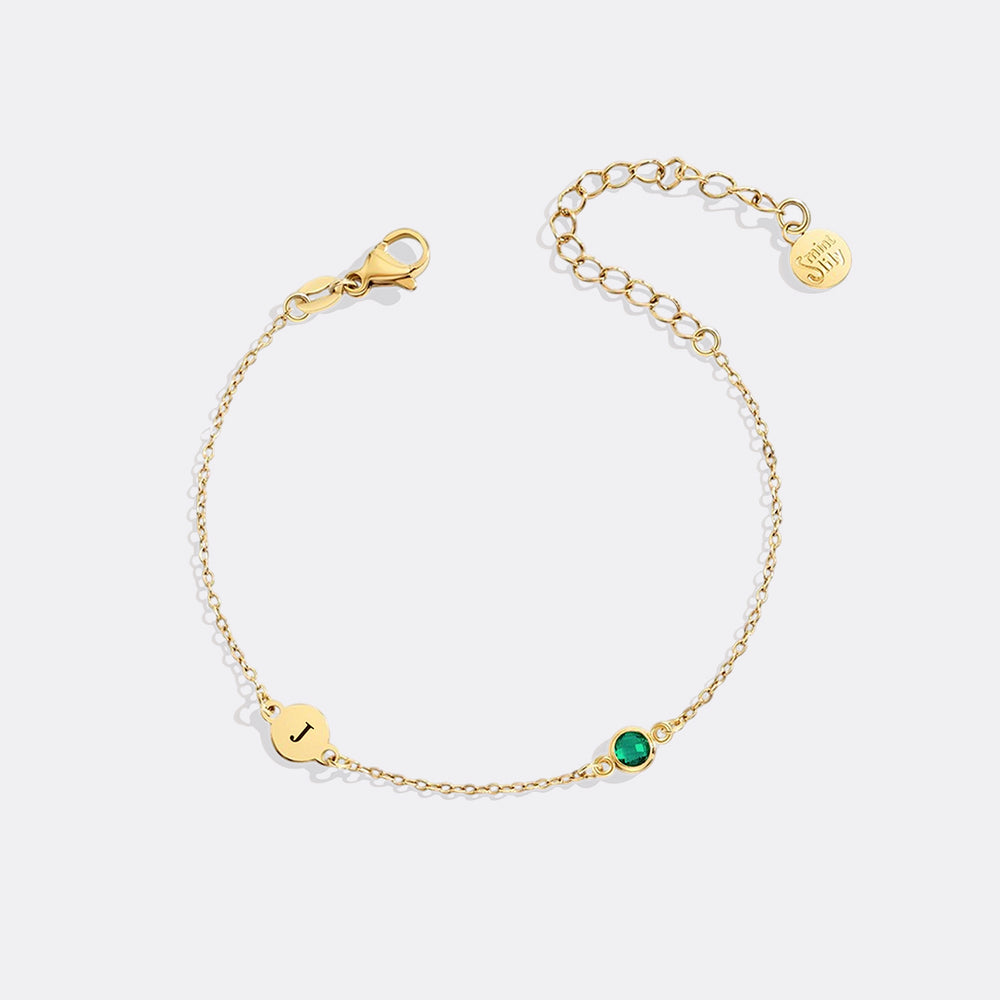 Gold bracelet with a green gemstone on a white background