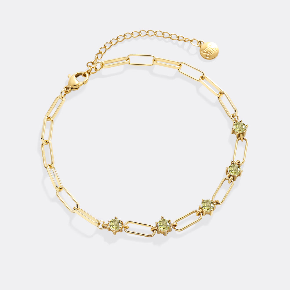 Gold bracelet with green gemstones on a white background