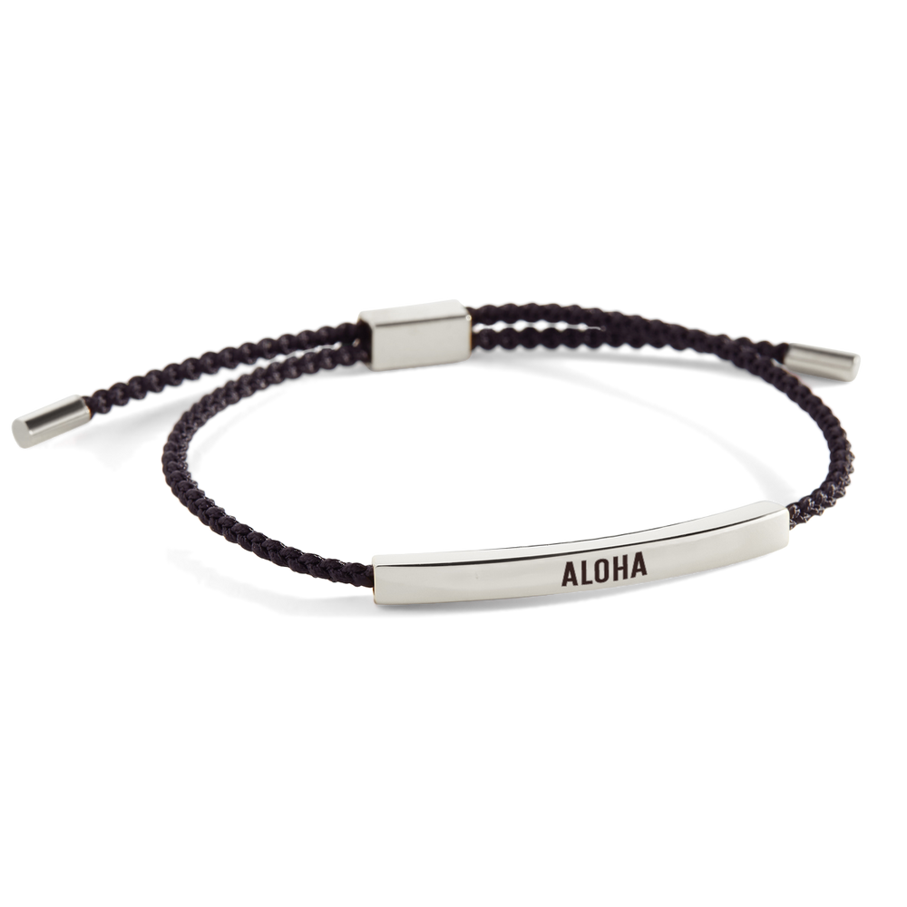 A bracelet with a silver-colored 'ALOHA' charm on a dark, possibly black, band. The word 'ALOHA' is also displayed in the upper part of the image.