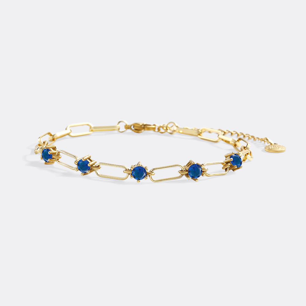 Gold bracelet with blue stones on a white background