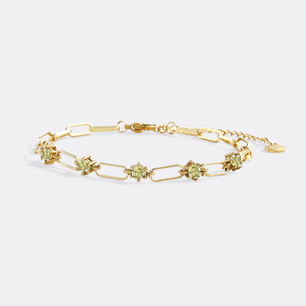 Gold bracelet with green gemstones on a white background