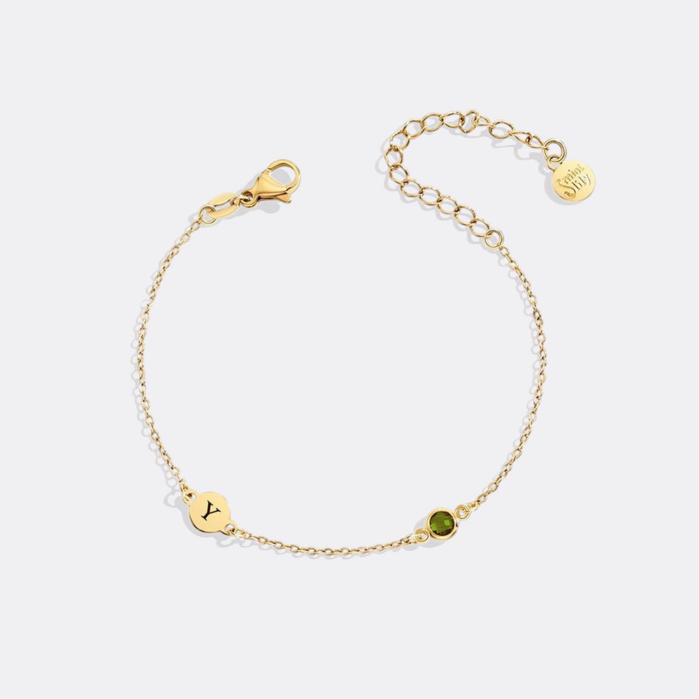 Gold bracelet with a green gemstone on a white background