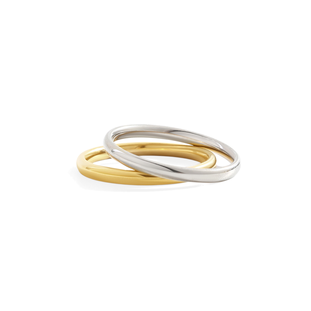 Two rings, one gold and one silver, on a light gray background