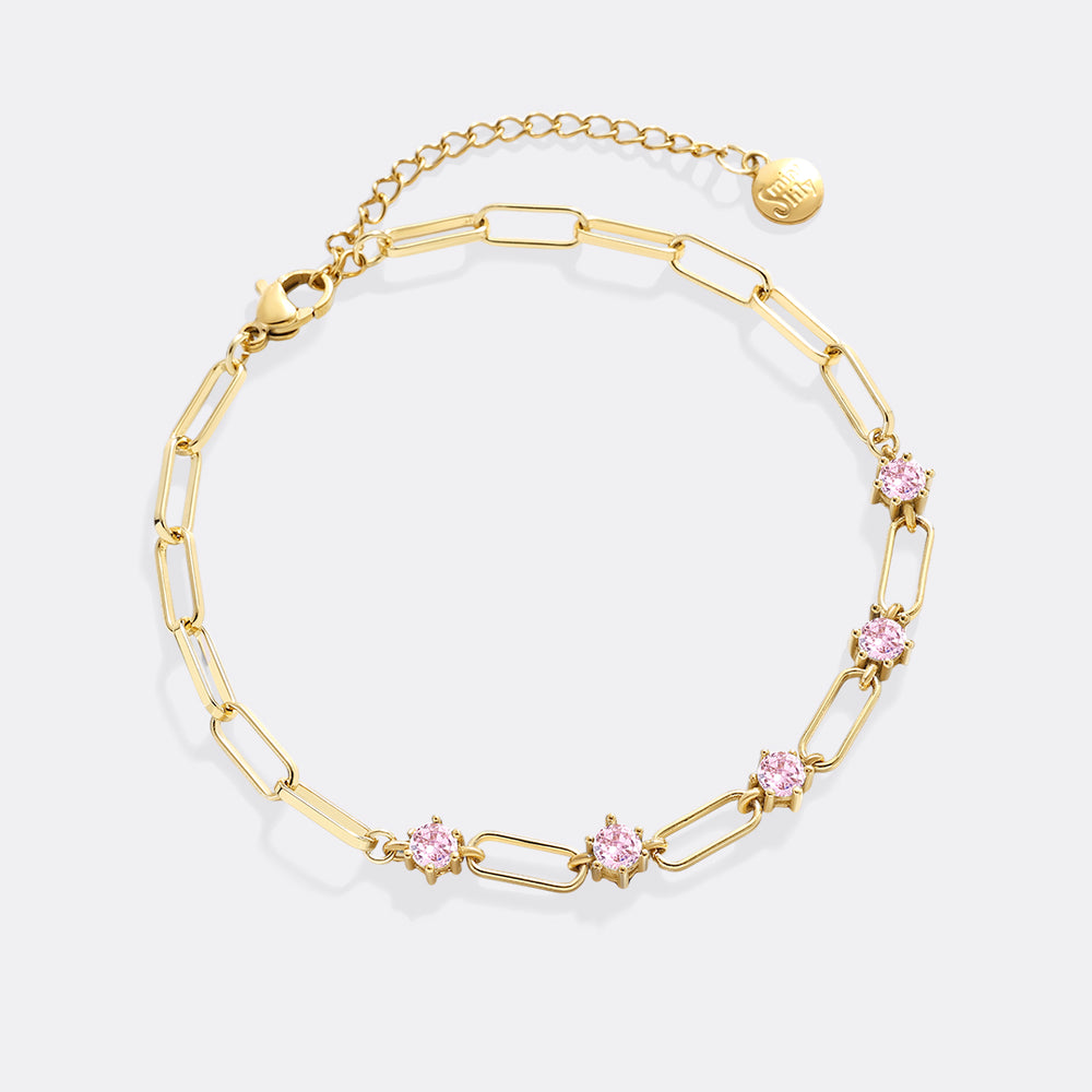 Gold bracelet with pink gemstones on a white background