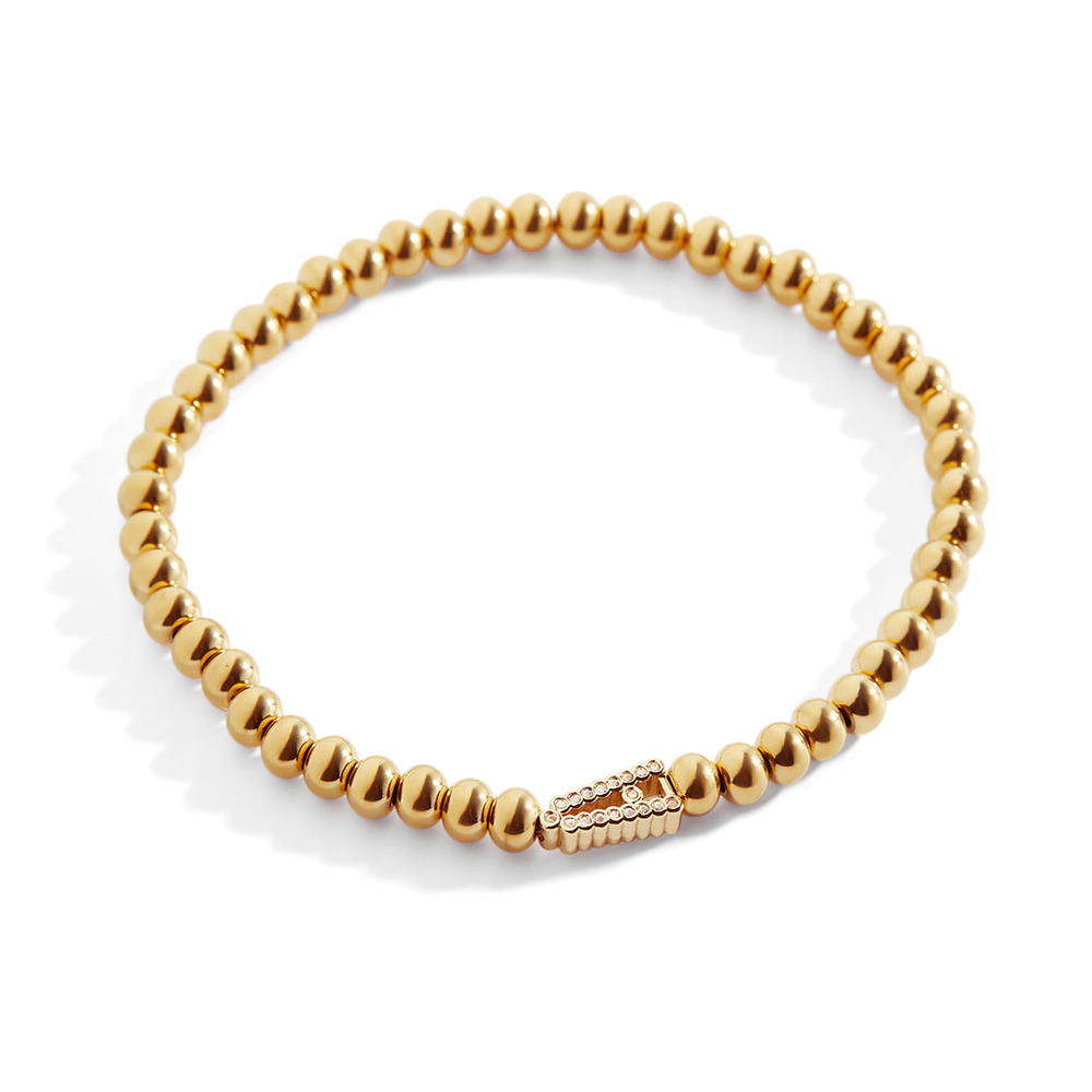 A gold-colored stretch bracelet with a sparkling diamond initial, featuring bead embellishments.
