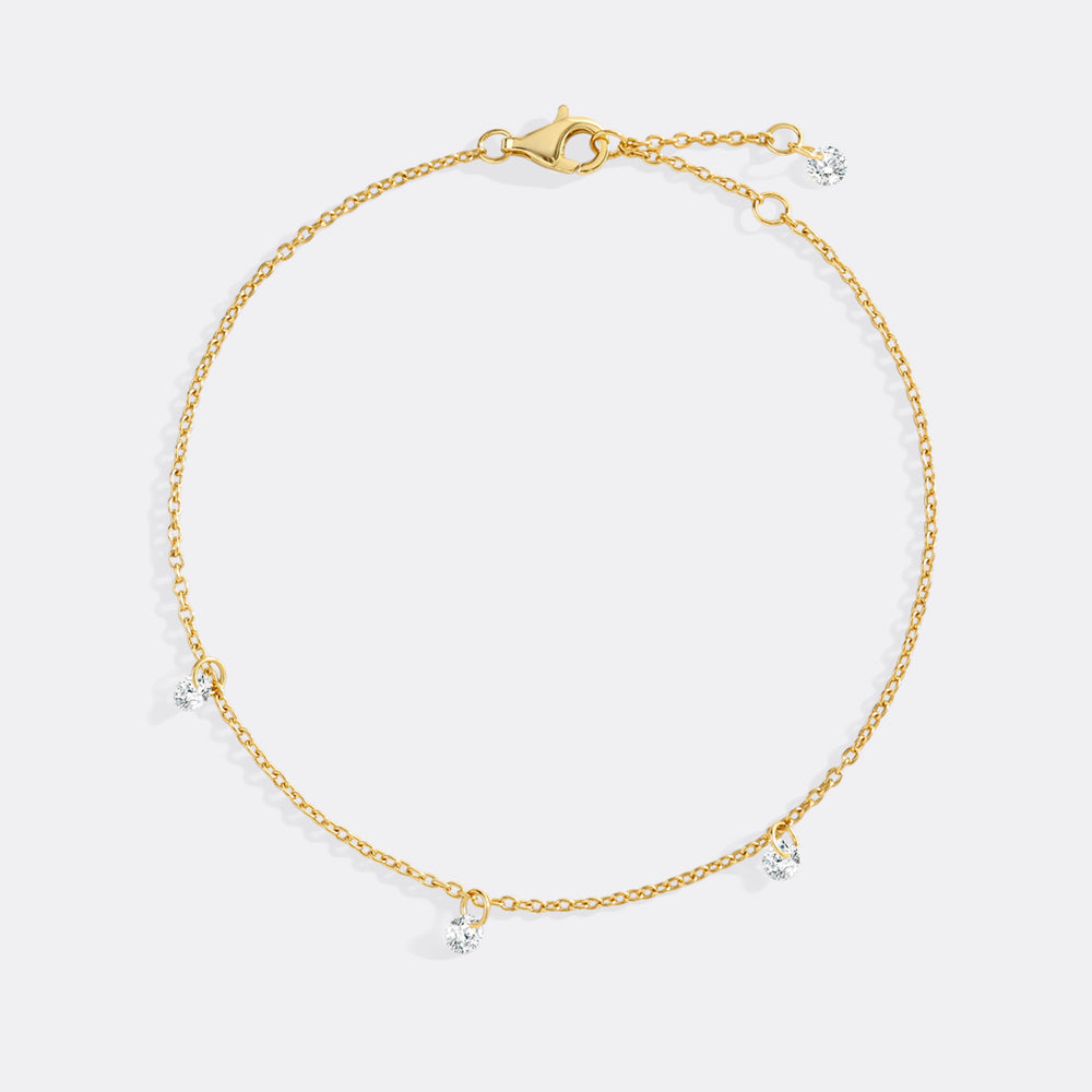Gold bracelet with small dangling charms on a light gray background