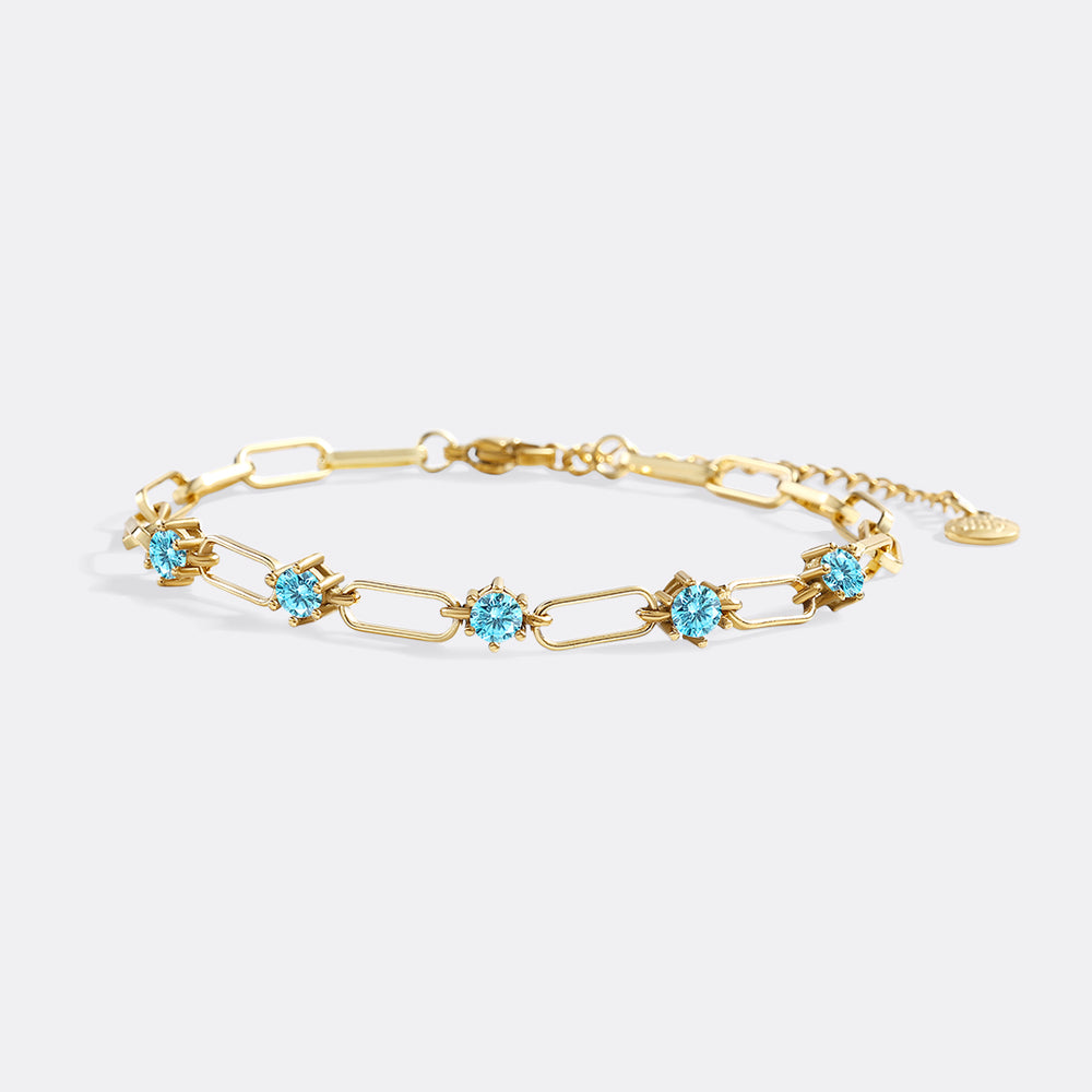 Gold bracelet with blue gemstones on a light gray background
