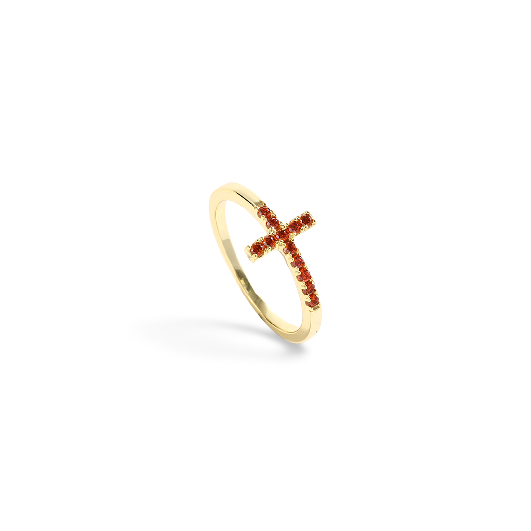 Gold ring with a red gemstone cross on a white background