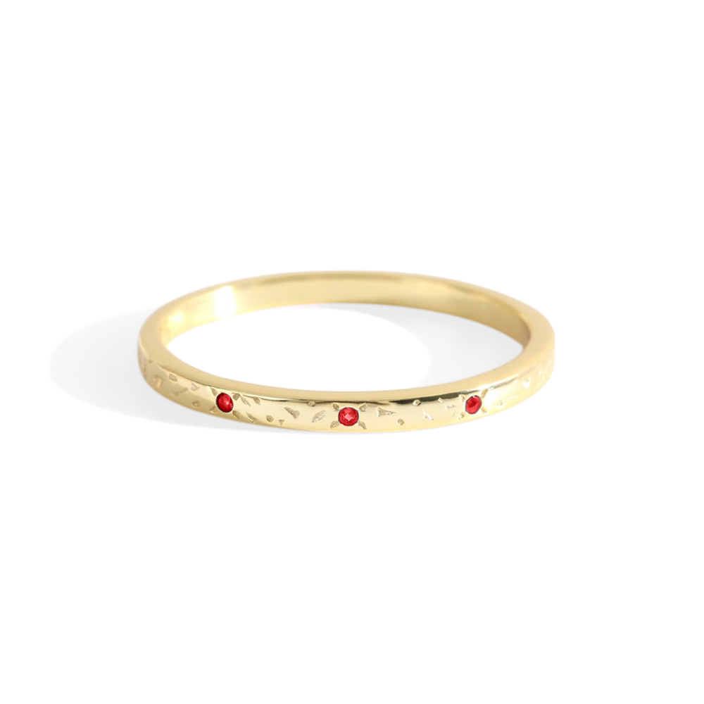 A thin gold band with red birthstones set at intervals along its length, displayed against a white background.