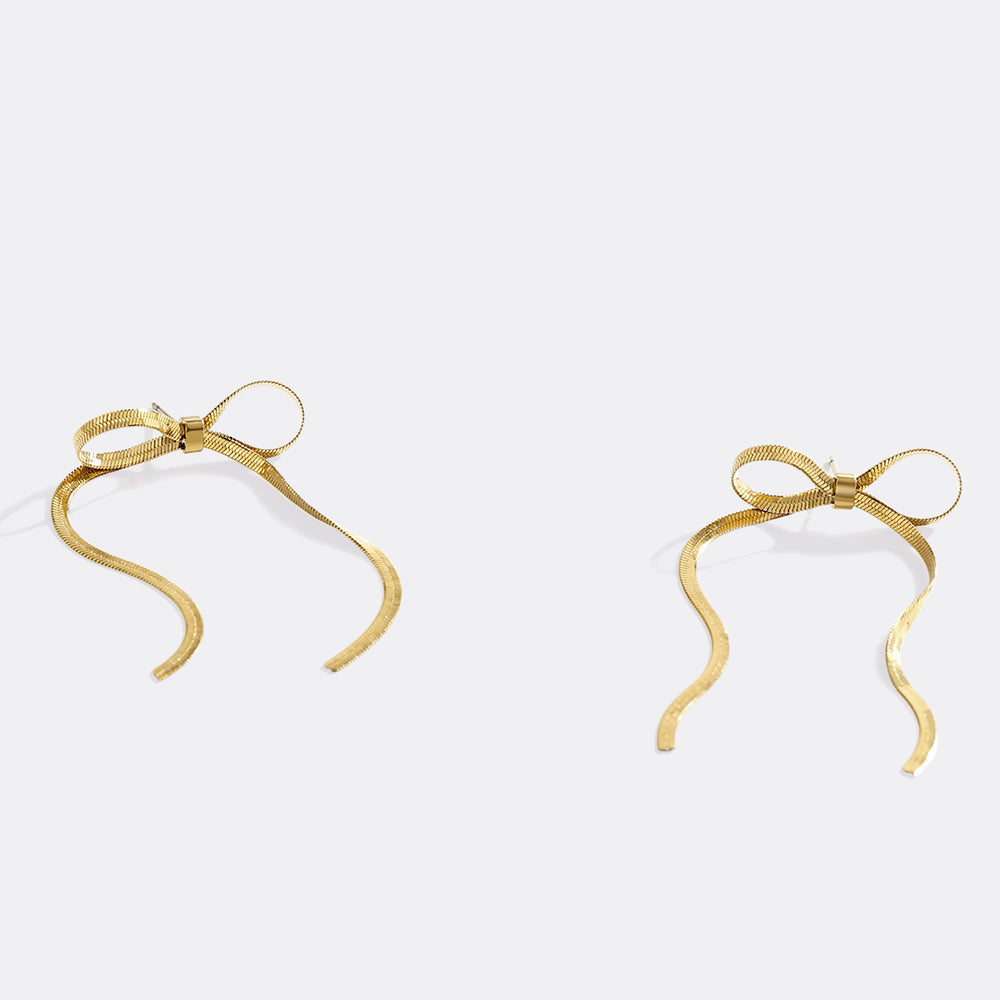 Gold bow-shaped earrings on a light gray background