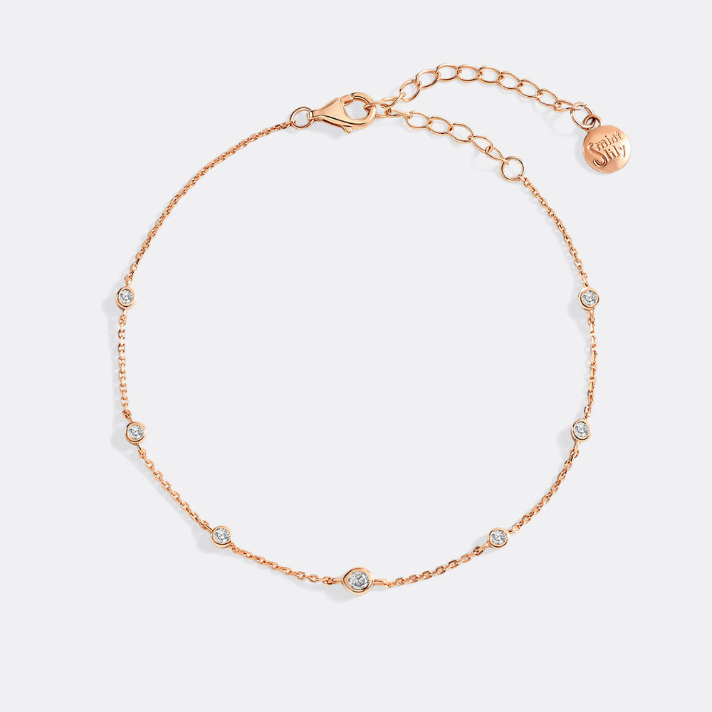 Rose gold bracelet with small diamonds on a light gray background