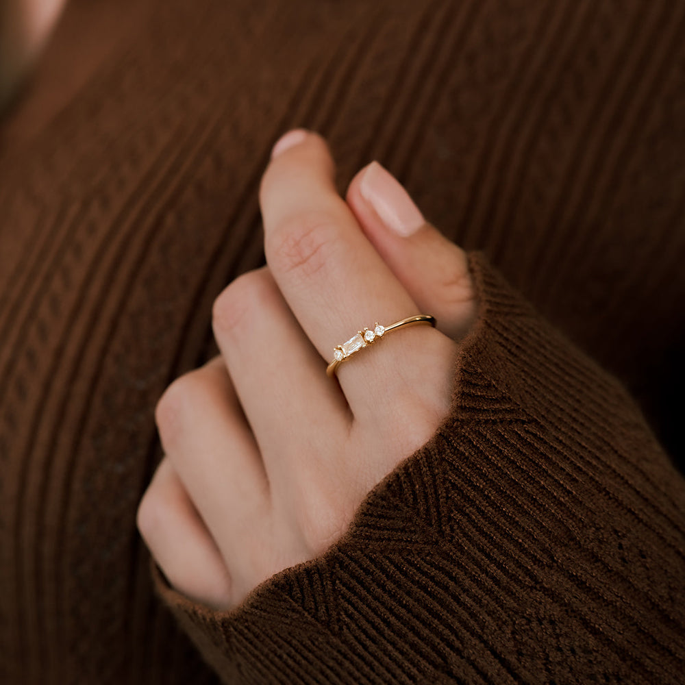 Close-up of a hand wearing a gold ring with a brown textured background