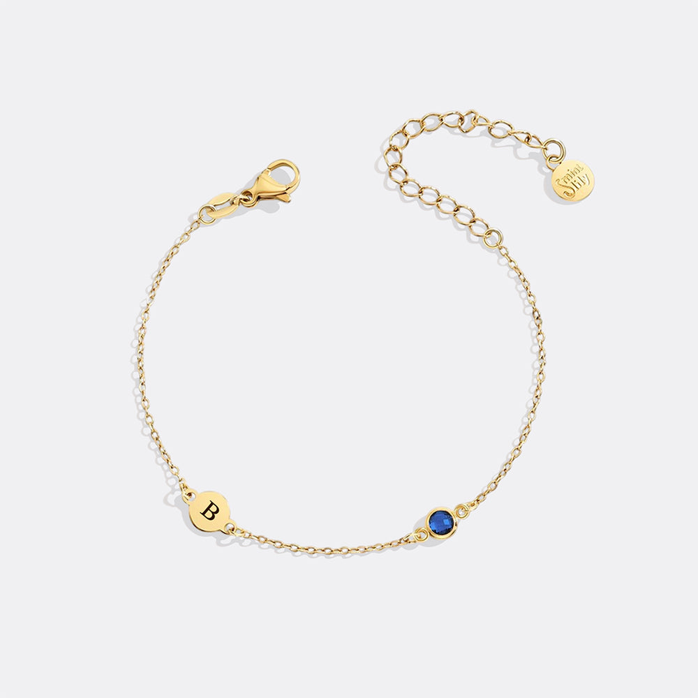 Gold bracelet with a blue gemstone on a white background