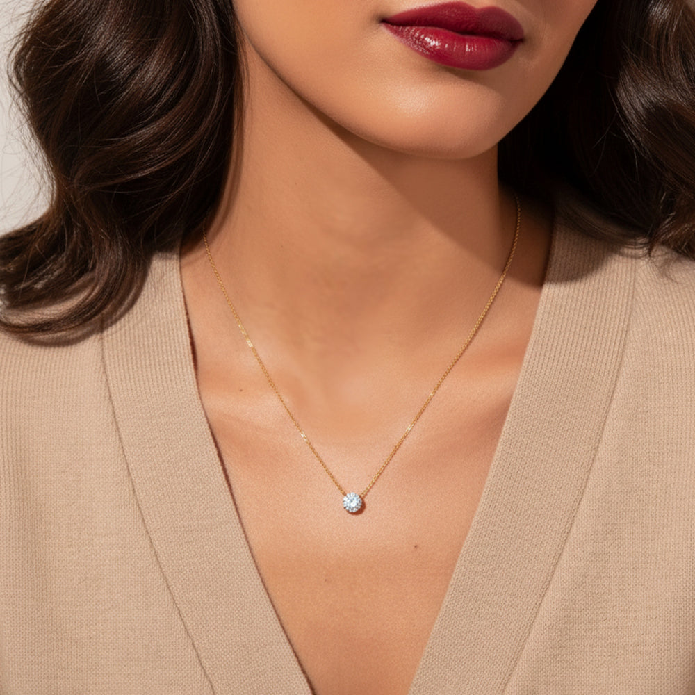Close-up of a woman wearing a gold necklace with a small pendant.