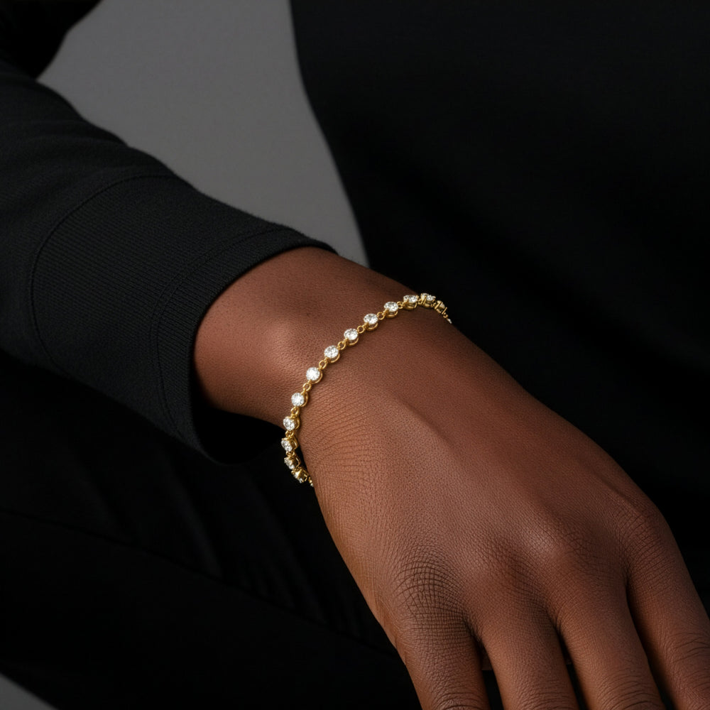 Gold bracelet on a wrist against a dark background