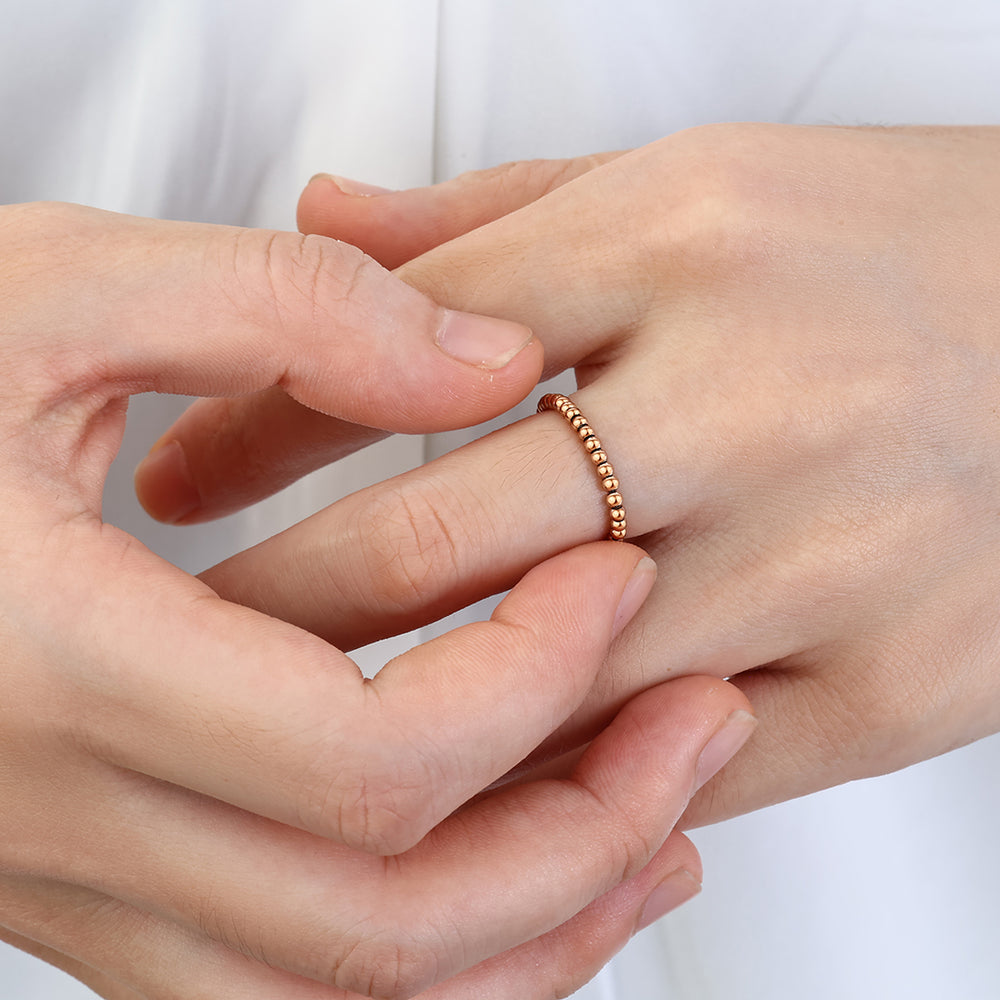 Close-up of a hand wearing a rose gold ring on a white background