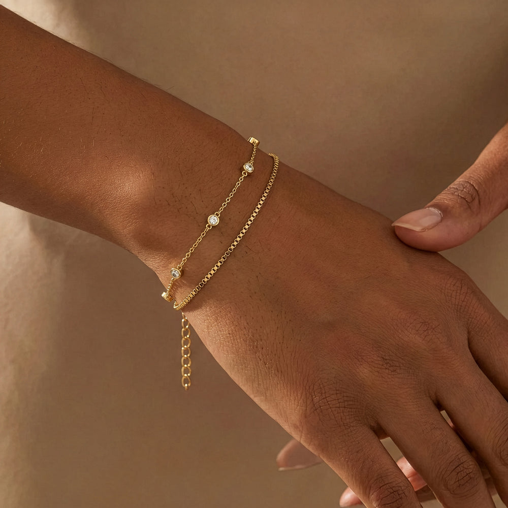 Hand wearing a gold bracelet on a neutral background