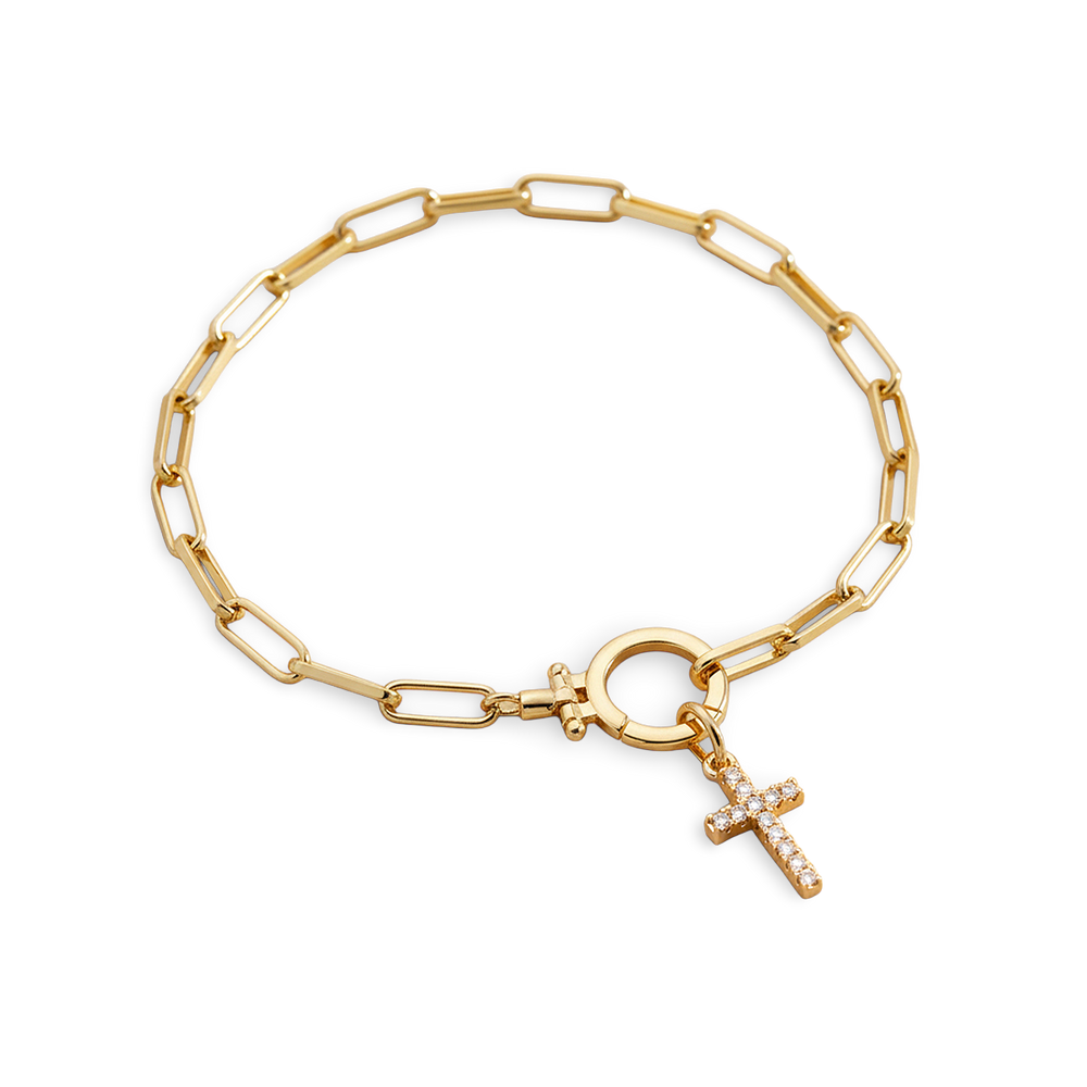 Gold chain bracelet with a cross charm on a light gray background