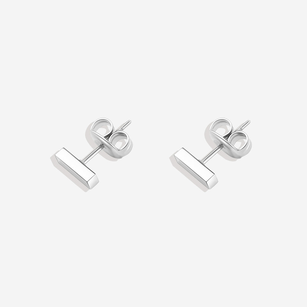 A pair of dainty bar stud earrings made of 18k gold over stainless steel, displayed against a black background.
