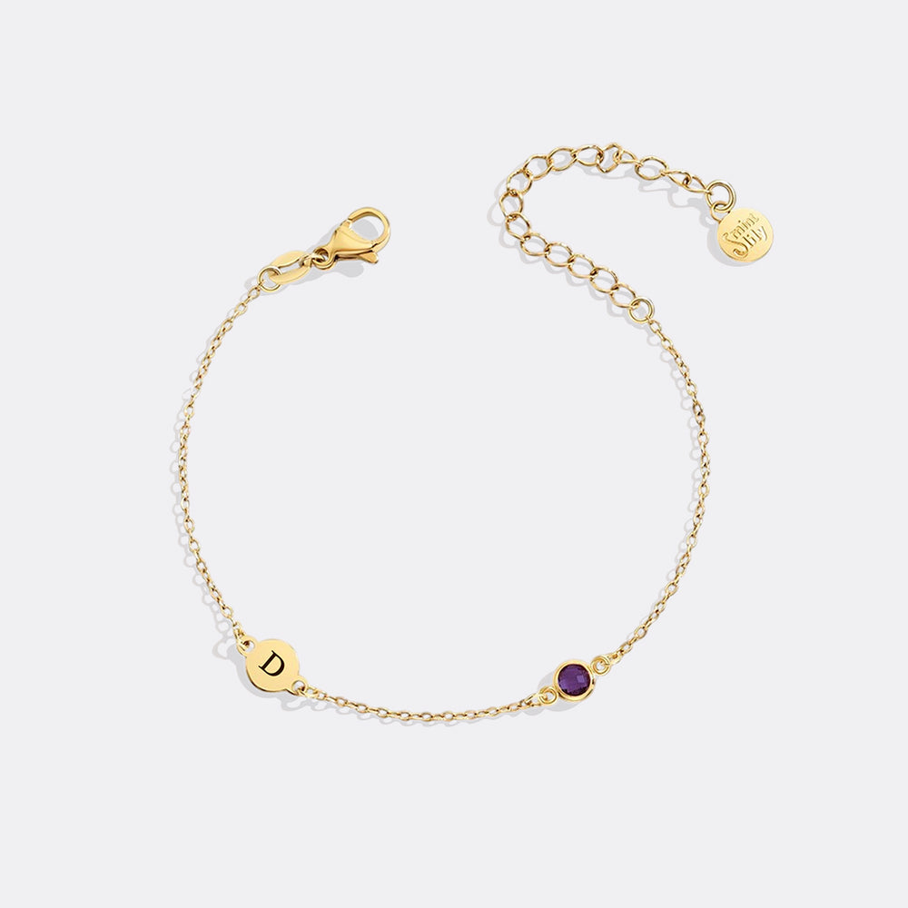 Gold bracelet with a purple gemstone on a white background