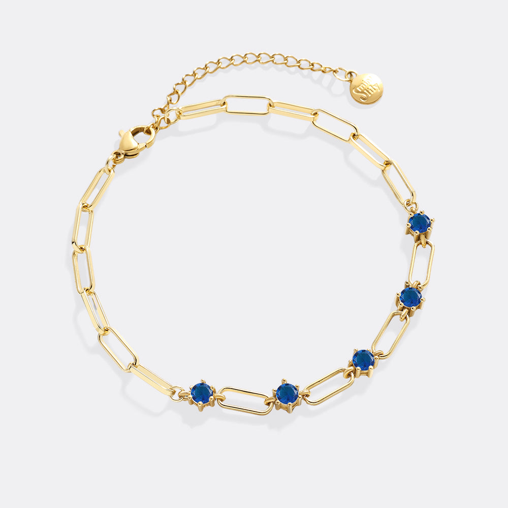 Gold bracelet with blue stones on a white background