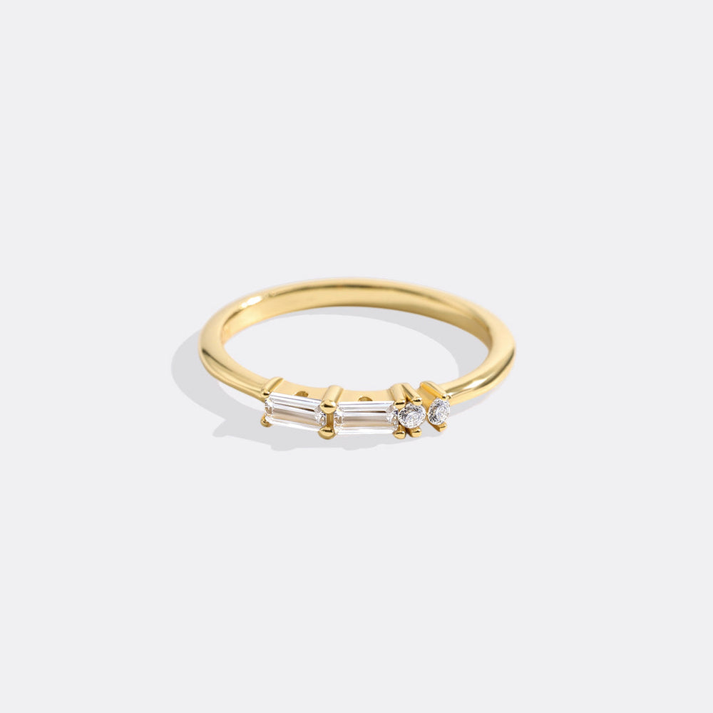 Gold ring with three diamonds on a light gray background