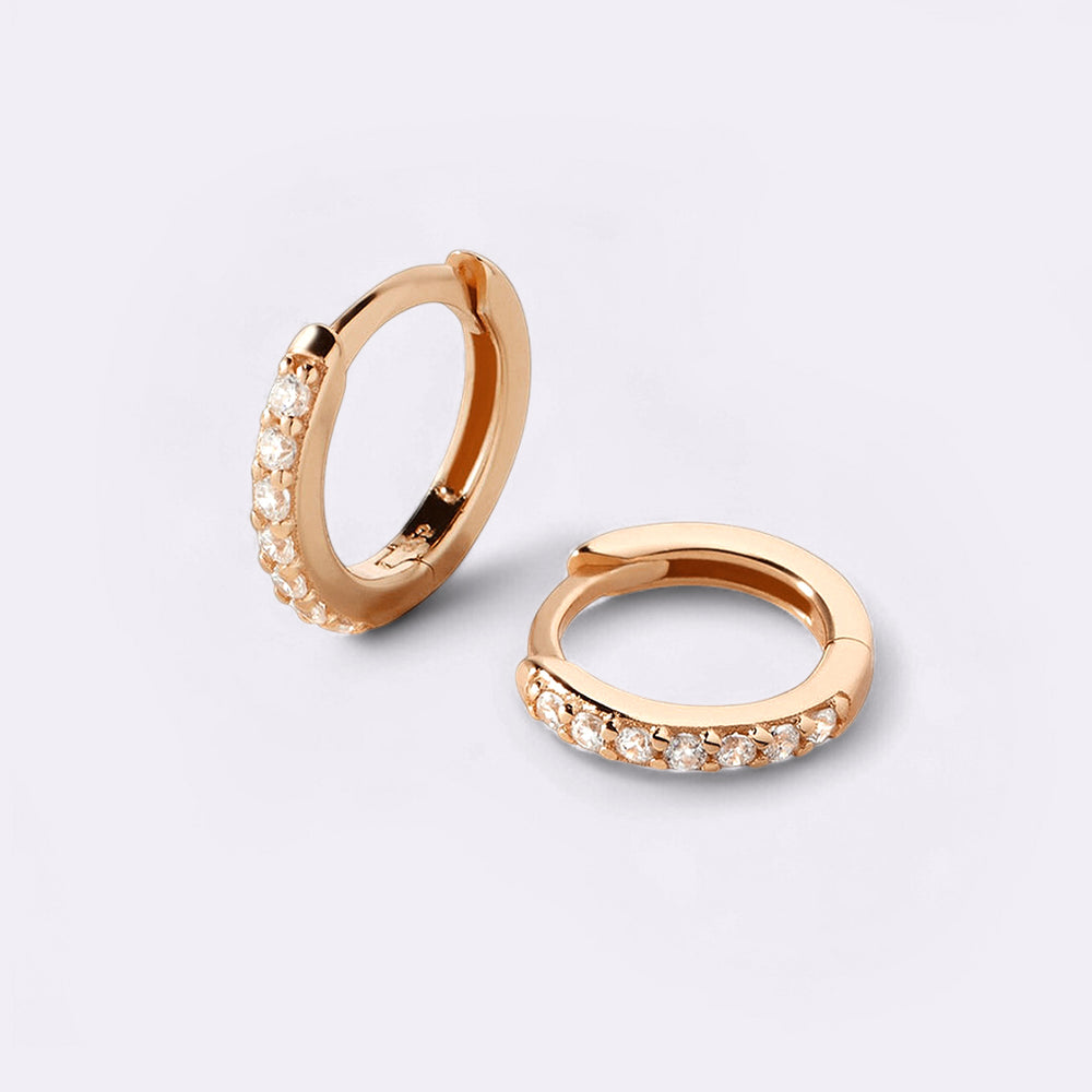 Rose gold hoop earrings with embedded stones on a light gray background