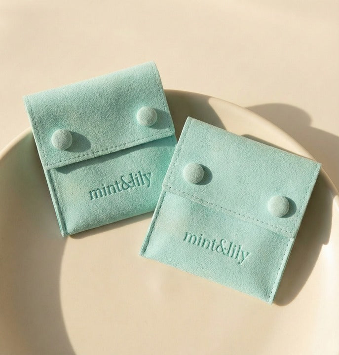 Two light blue jewelry pouches with 'mint&lily' branding on a beige background
