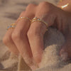 slow motion hand in the sand with rings on