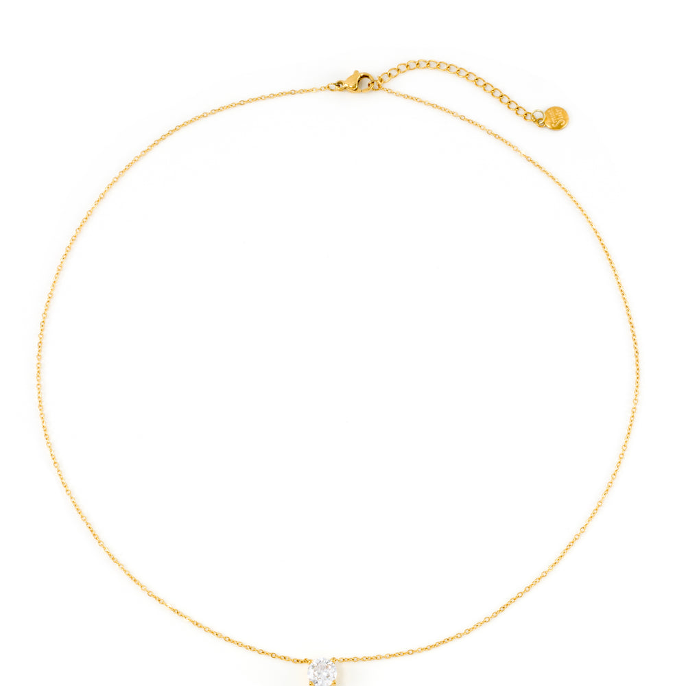 Gold solitaire pendant necklace laid flat on a white background, shown in full from clasp to clasp with its extender chain.