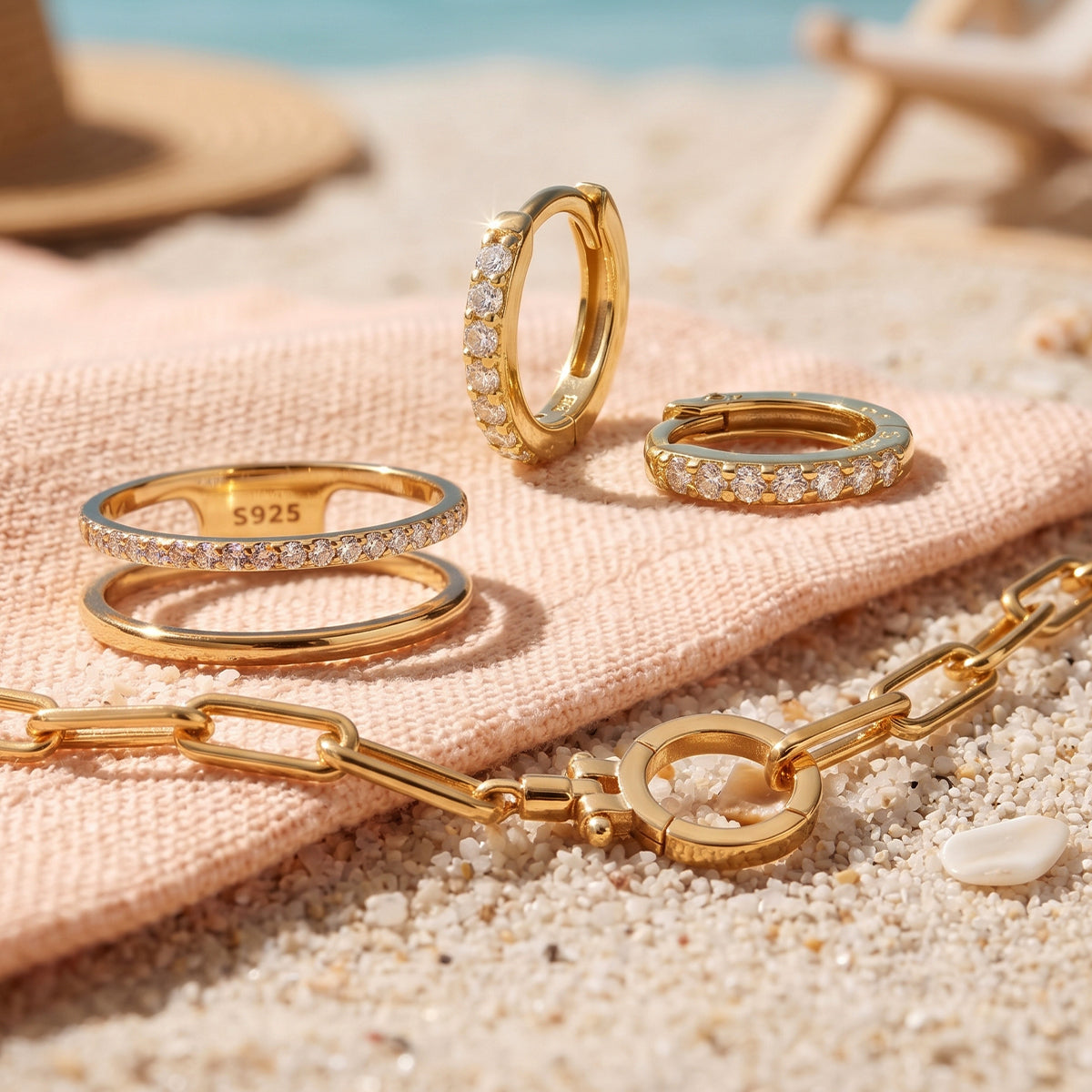 Gold rings and necklace on a pink cloth with a beach background