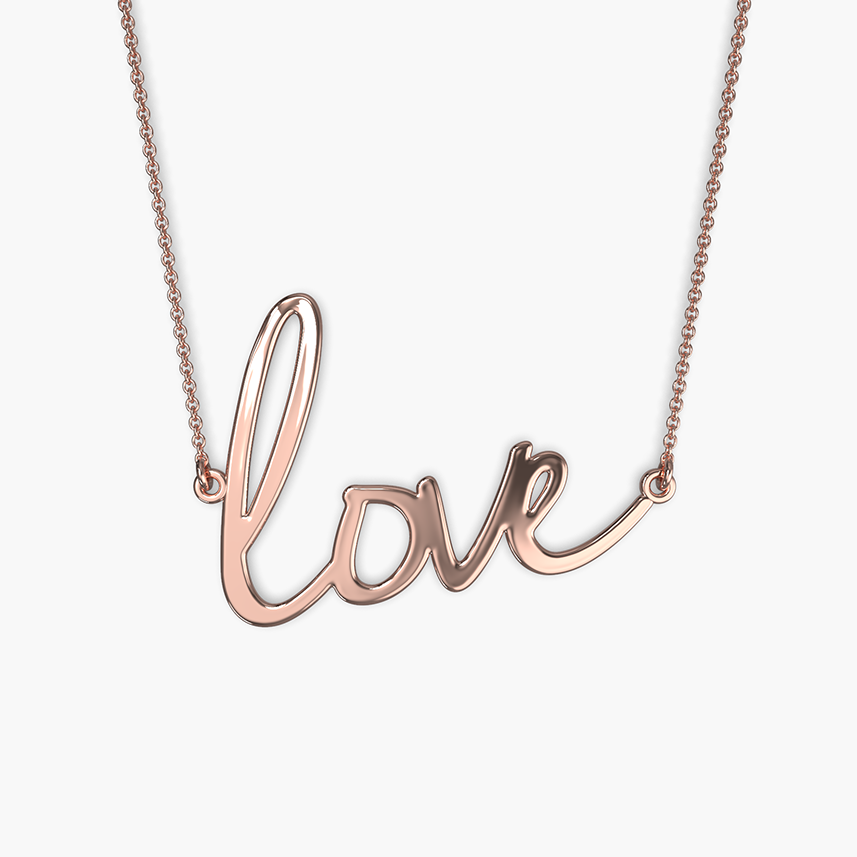 A person wearing a white V-neck top showcasing a gold-colored necklace with the word 'love' written in cursive script.